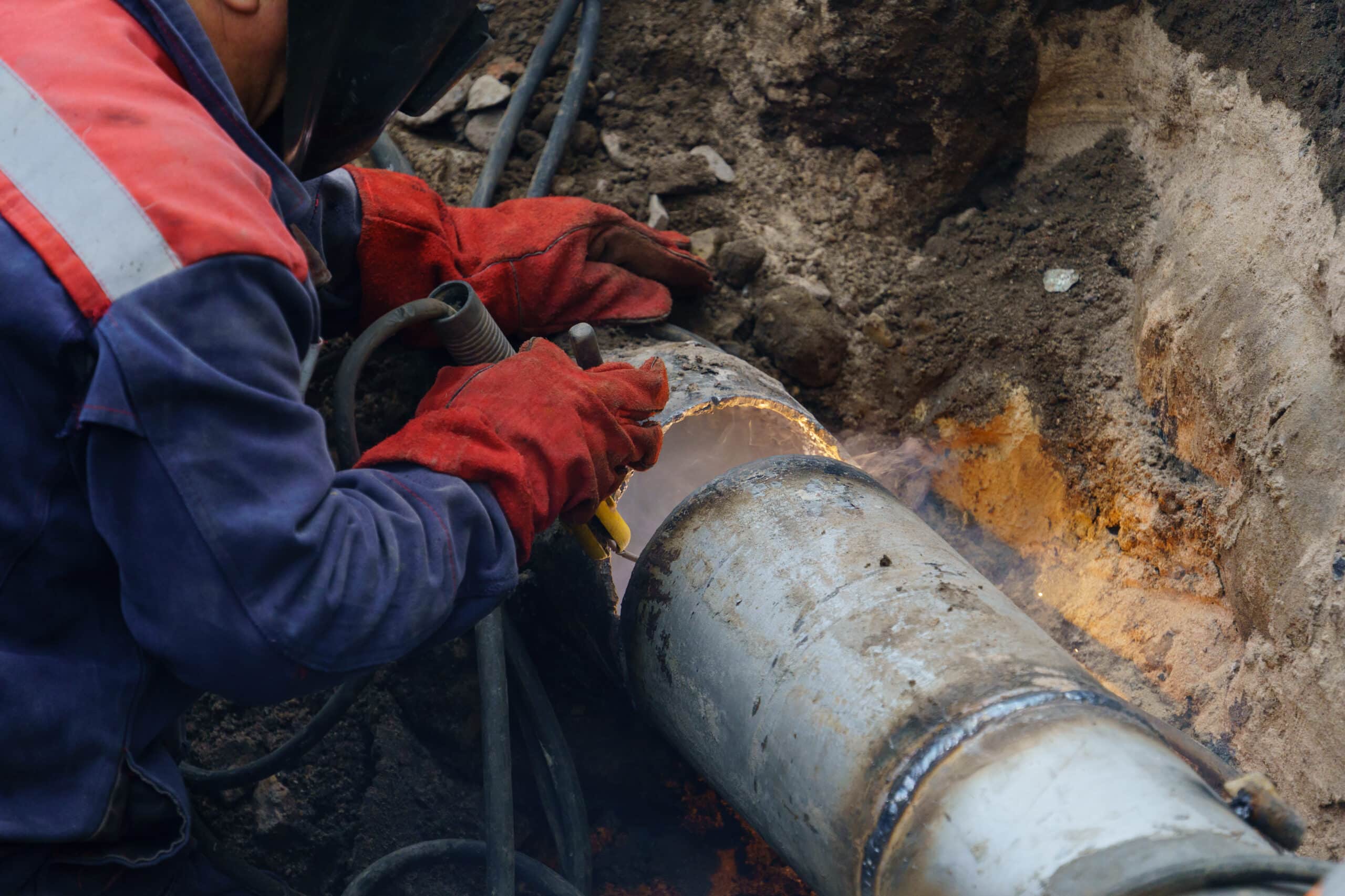 Utility worker fixing broken water main. Sewerage pipe repair concept.